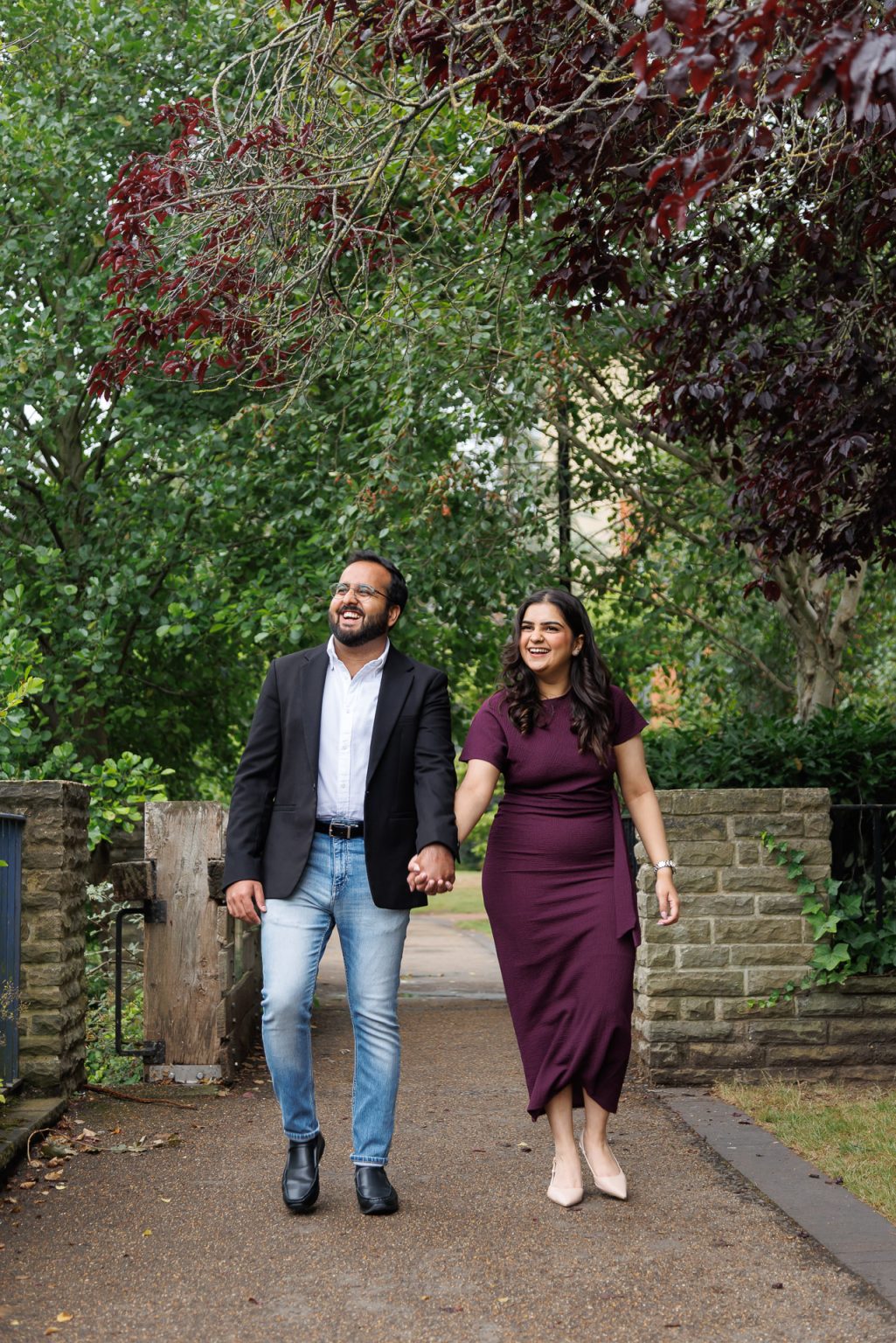 Jordan Taylor C Photography - Candid moment of couple smiling on Oxford cobblestone streets during their UK engagement shoot, walking hand in hand by the canals.