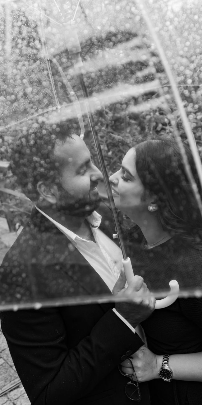 Close-up portrait of engaged couple in Oxford city centre during their Oxfordshire engagement session, close under an umbrella.