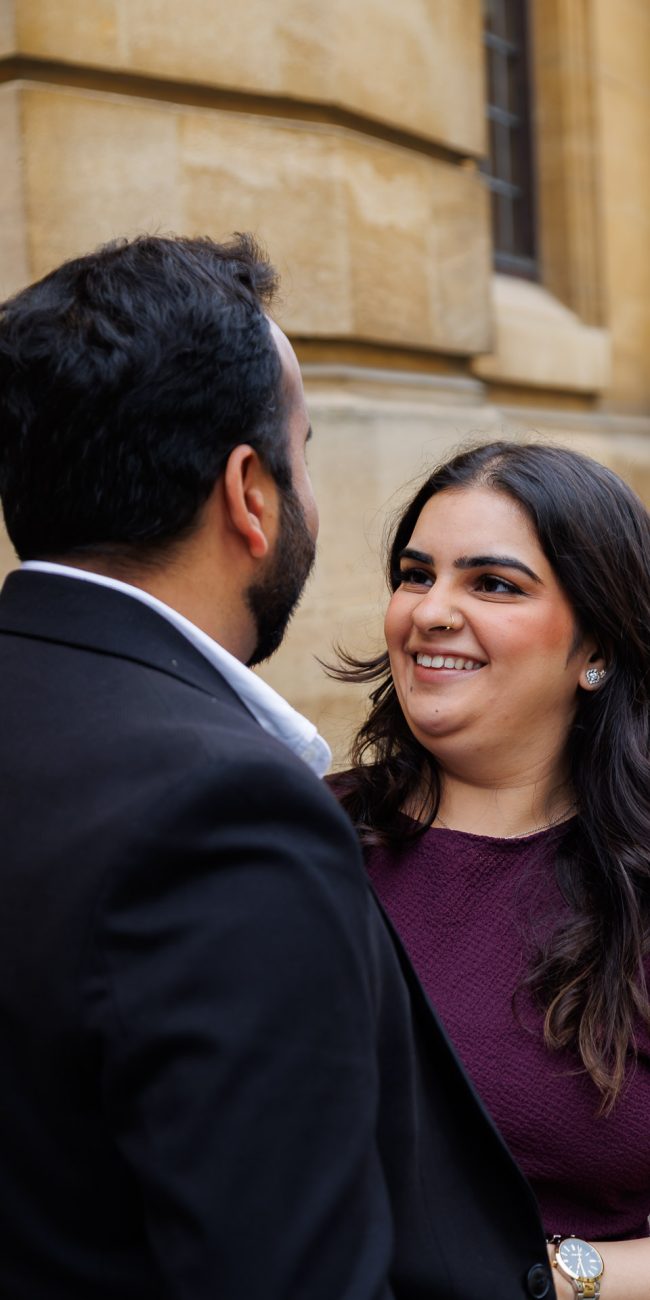 Couple walking hand-in-hand in front of the Radcliffe Camera during their Oxford engagement shoot, photographed by an London based wedding photographer.