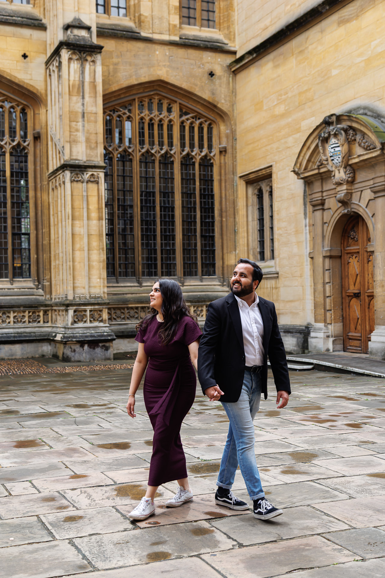 Couple walking hand-in-hand in front of the Radcliffe Camera and Bodleian Library during their Oxford engagement shoot, photographed by a London-based wedding photographer.